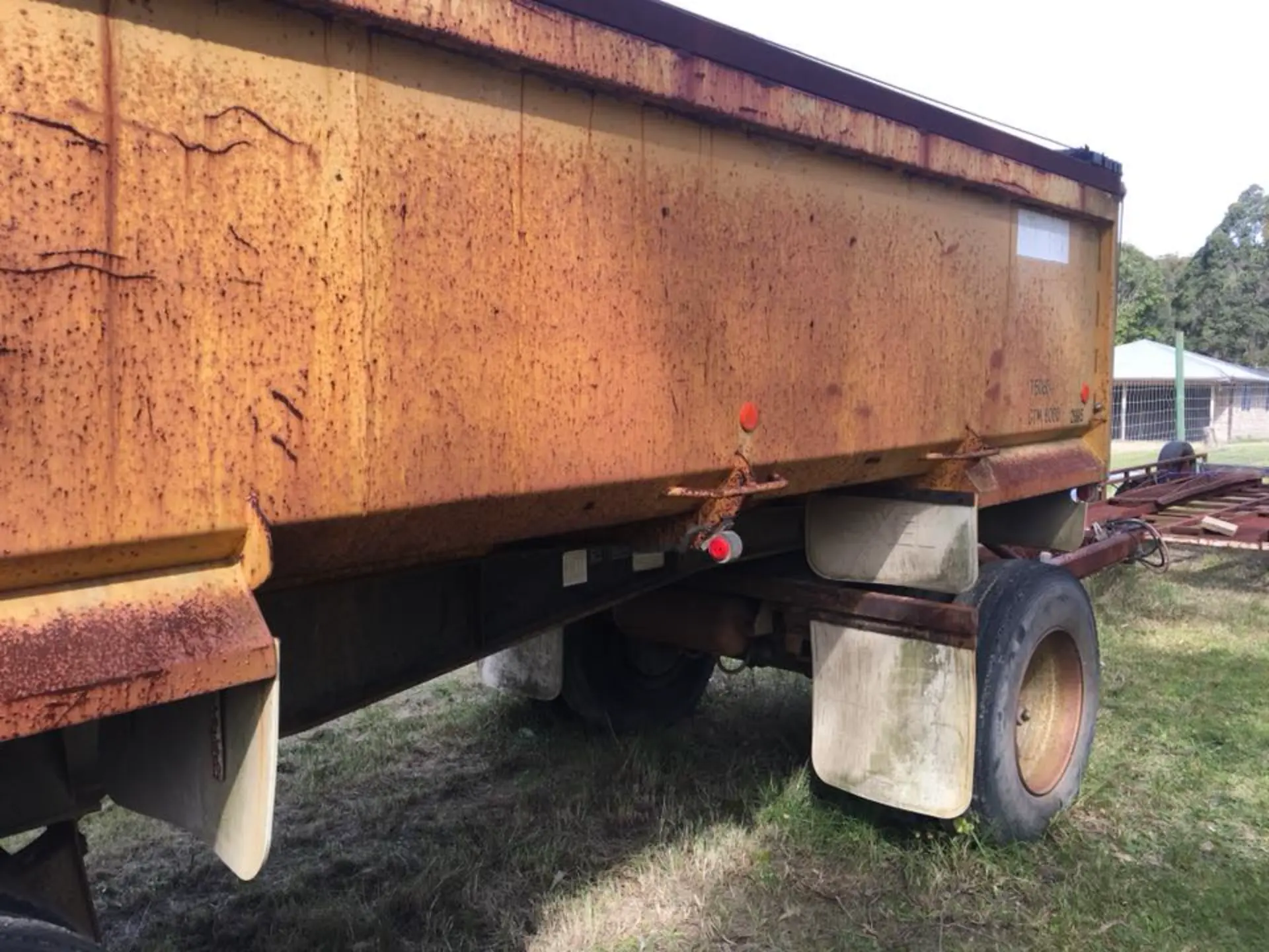 Close view of a tipper trailer body streaked with heavy surface rust before blasting